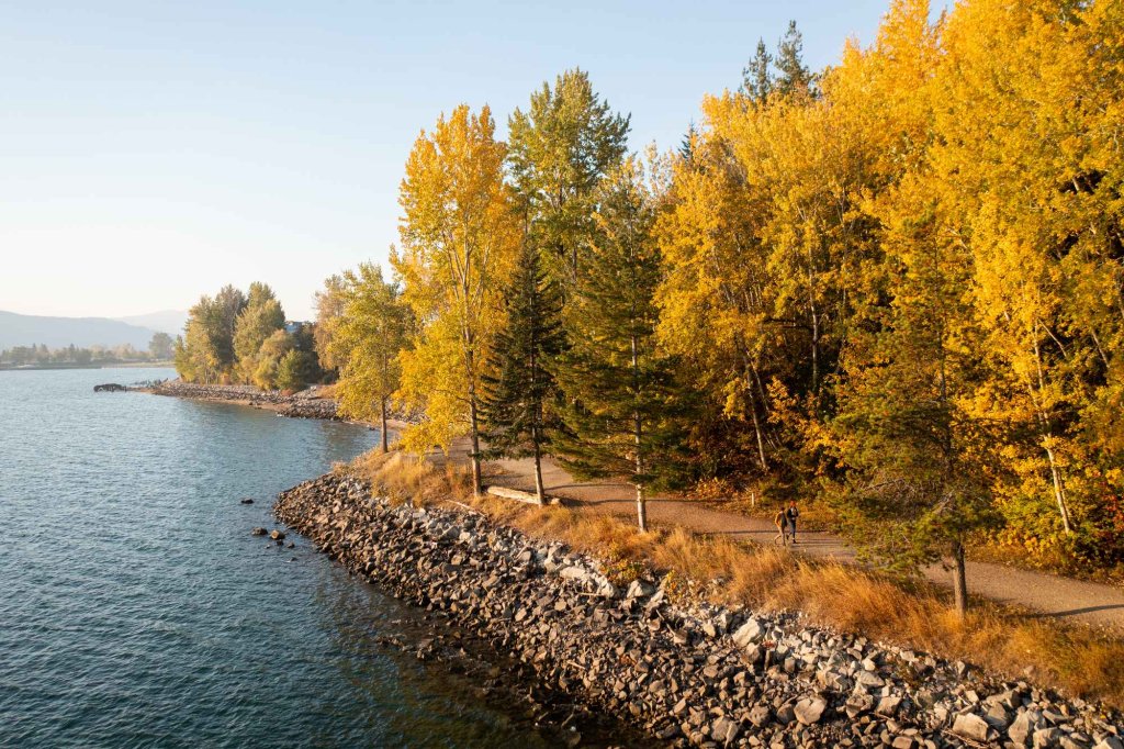 The Pend d'Oreille Bay Trail, lined with trees with fall colors, along Lake Pend d'Oreille.