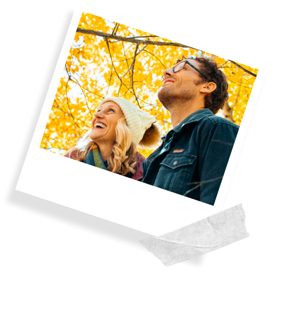 A taped Polaroid image showing a man and woman gazing up at a canopy of yellow tree leaves in a forest at Tamarack Resort.