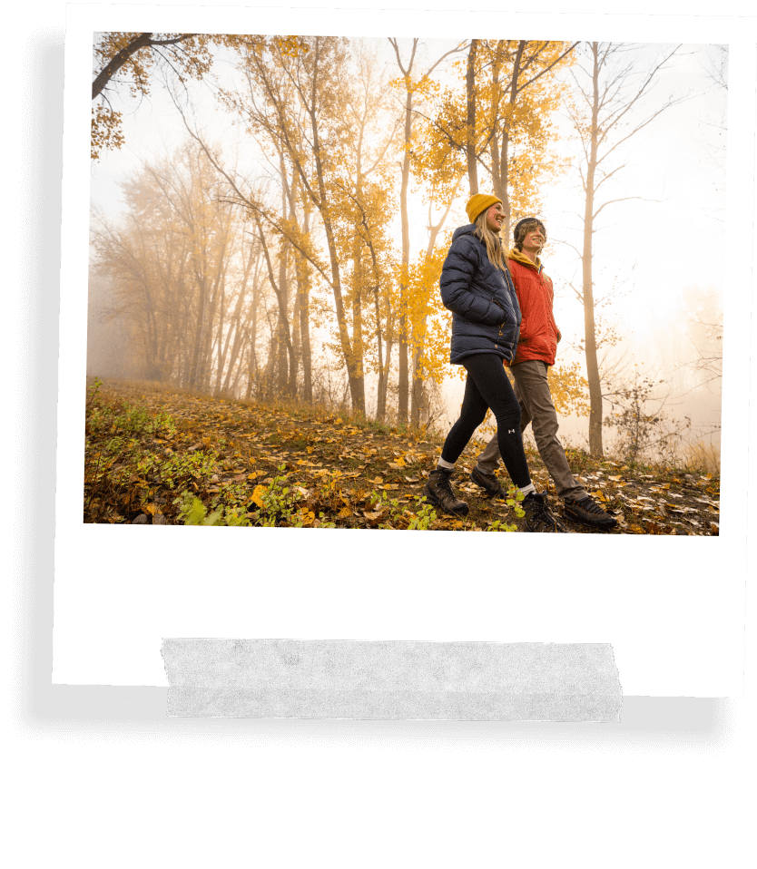 A taped Polaroid image showing a man and woman walking along the Deep Creek Trail surrounded by trees with fall foliage at Kootenai Wildlife Refuge.