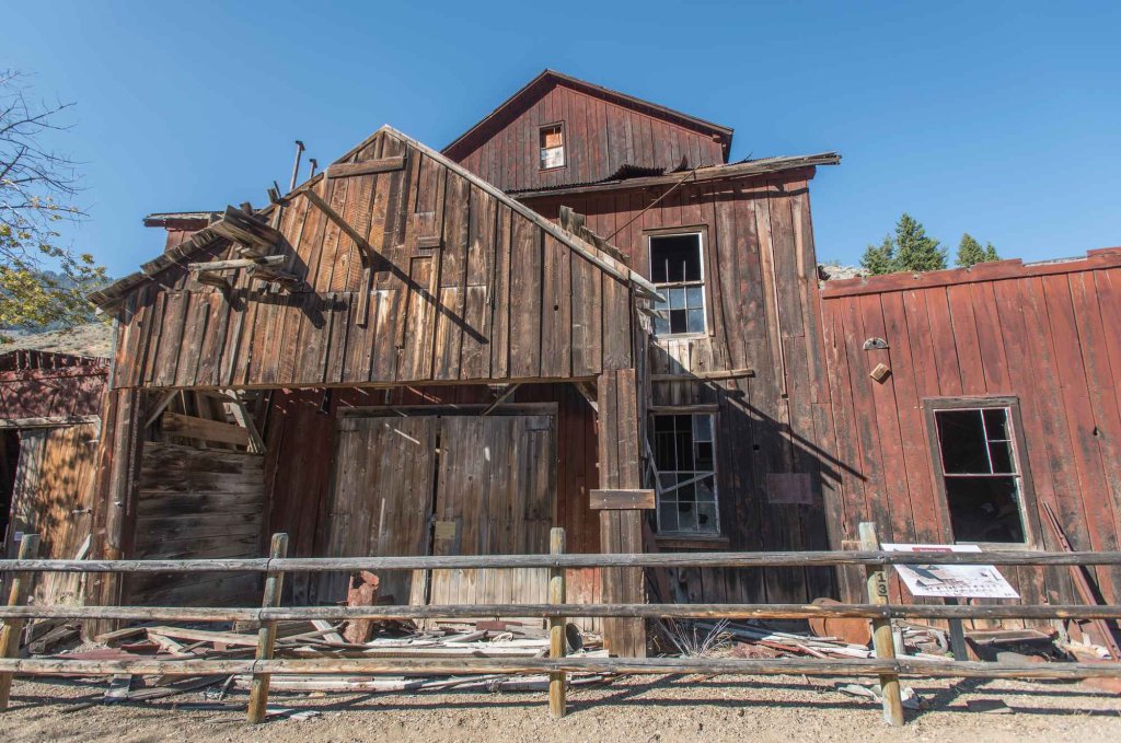 Weathered wooden buildings at Bayhorse Ghost Town under a clear blue sky.