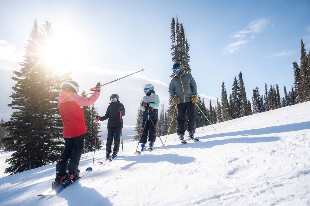 Skier family group standing on a snowy slope at Tamarack Resort under a bright winter sun