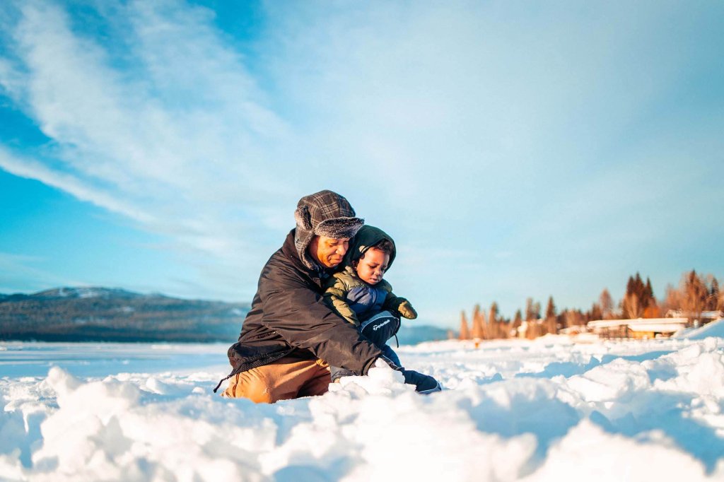 Adult and child playing together in the snow on a frozen Payette Lake near McCall, Idaho