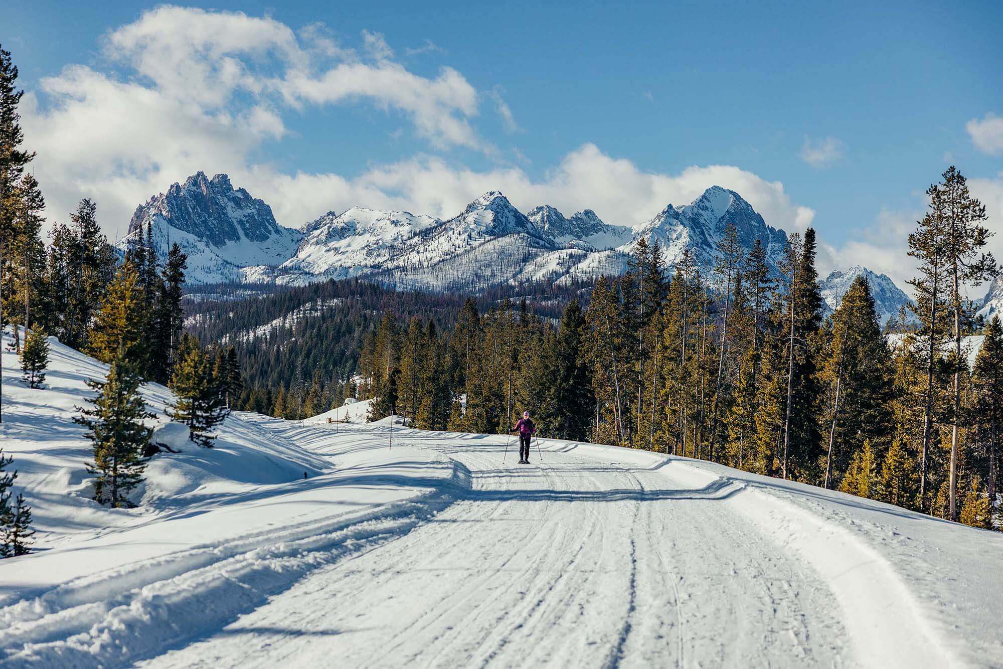 Cross-country skier on Redfish Lake Road with the Sawtooth Mountains in the background, near Stanley, Idaho