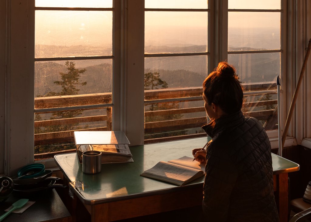 Visitor writing in the guest journal at the Lookout Butte fire lookout rental in the Idaho panhandle.