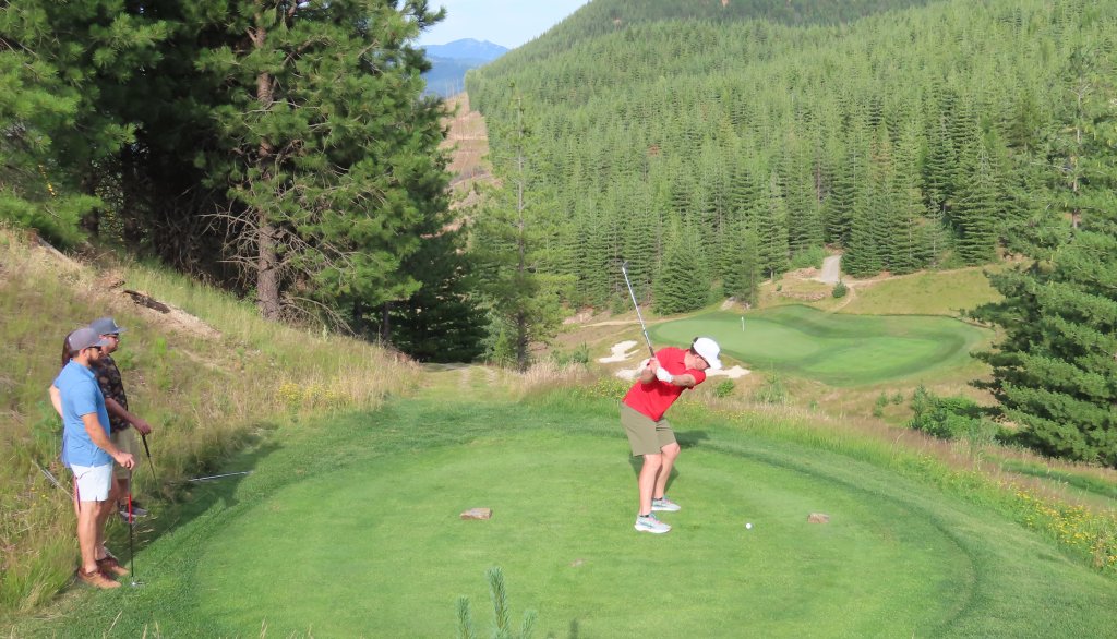 A group of people standing on a golf green surrounded by forests at the Galena Ridge Golf Course at Silver Mountain Resort.