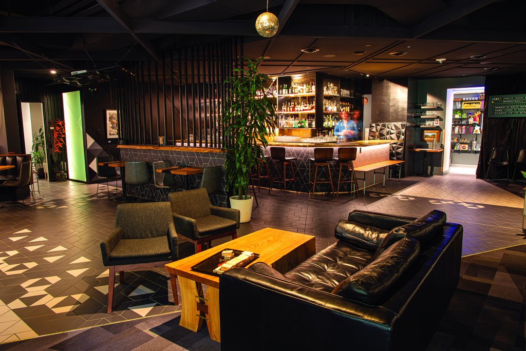 Close-up of Thick as Thieves interior in Boise, showing a portrait of three women between velvet curtains in a backroom with vintage chairs.