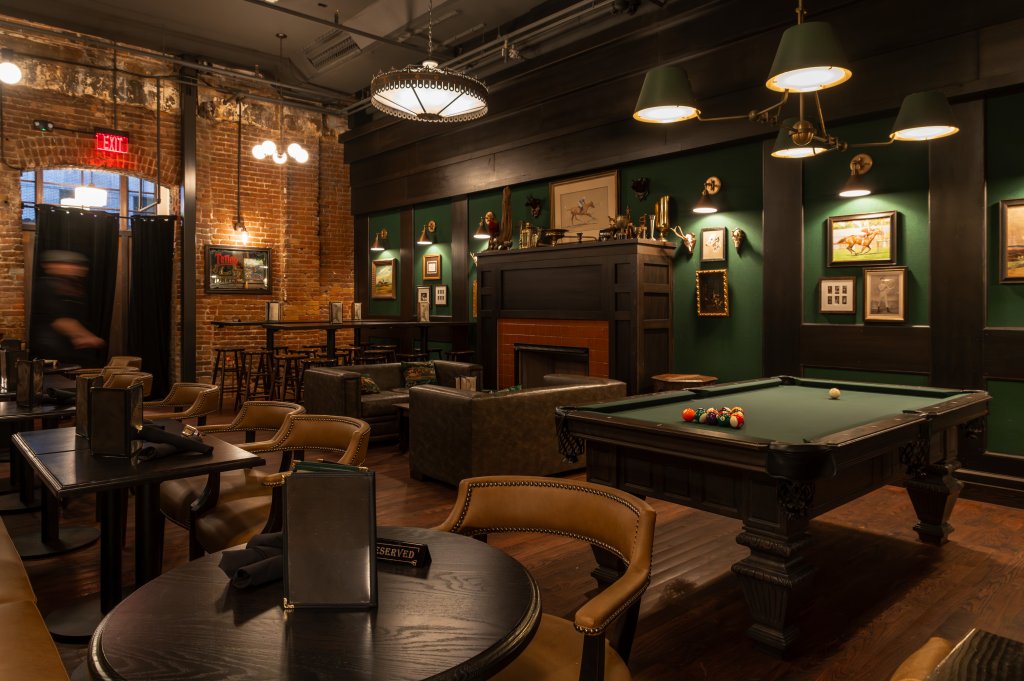 Interior of Tiner&rsquo;s Alley pub in Boise, showing a pool table, reserved tables, and couches by the fireplace.