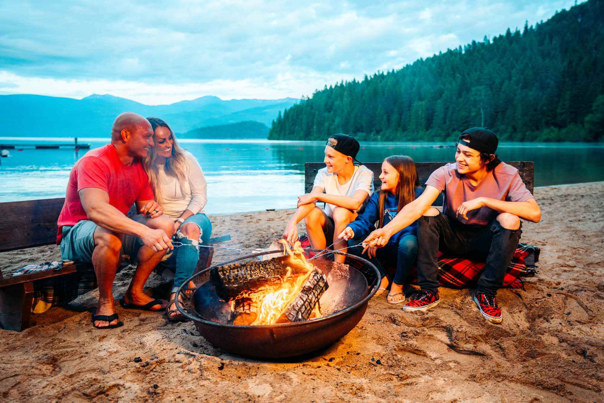 A family roast marshmallows around a campfire on the beach at Priest Lake.