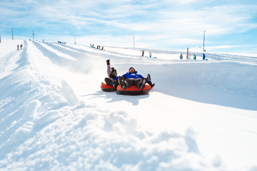 Two people snowtube down a hill at the McCall Activity Barn near McCall.