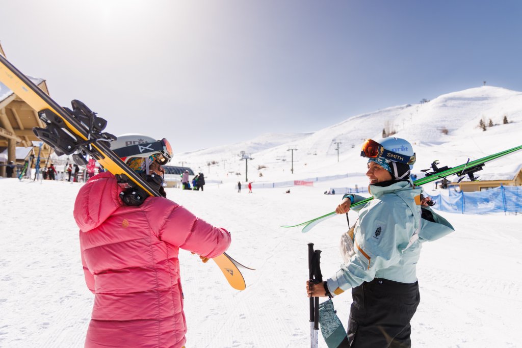 Two skiers with their gear smile at each other at Dollar Mountain in Sun Valley.