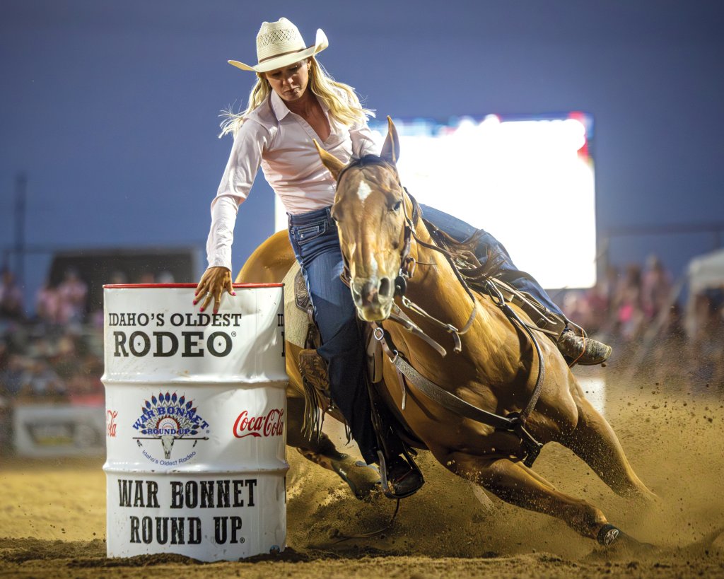 A woman barrel races around a barrel with her horse at the War Bonnet Round Up in Idaho Falls.