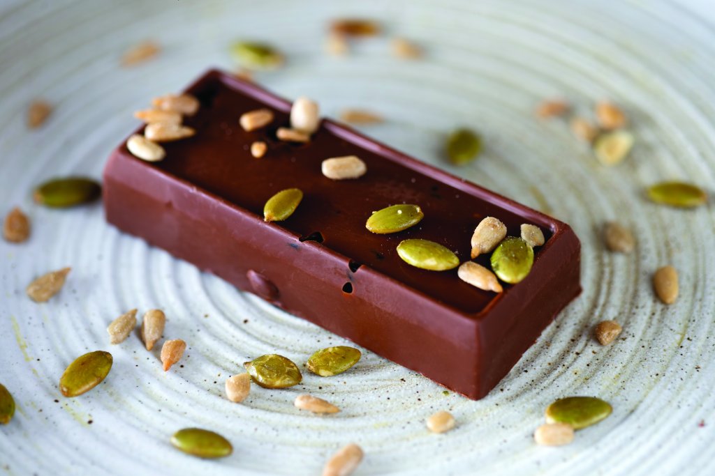 A delicious looking chocolate bar with sunflower seeds on top.