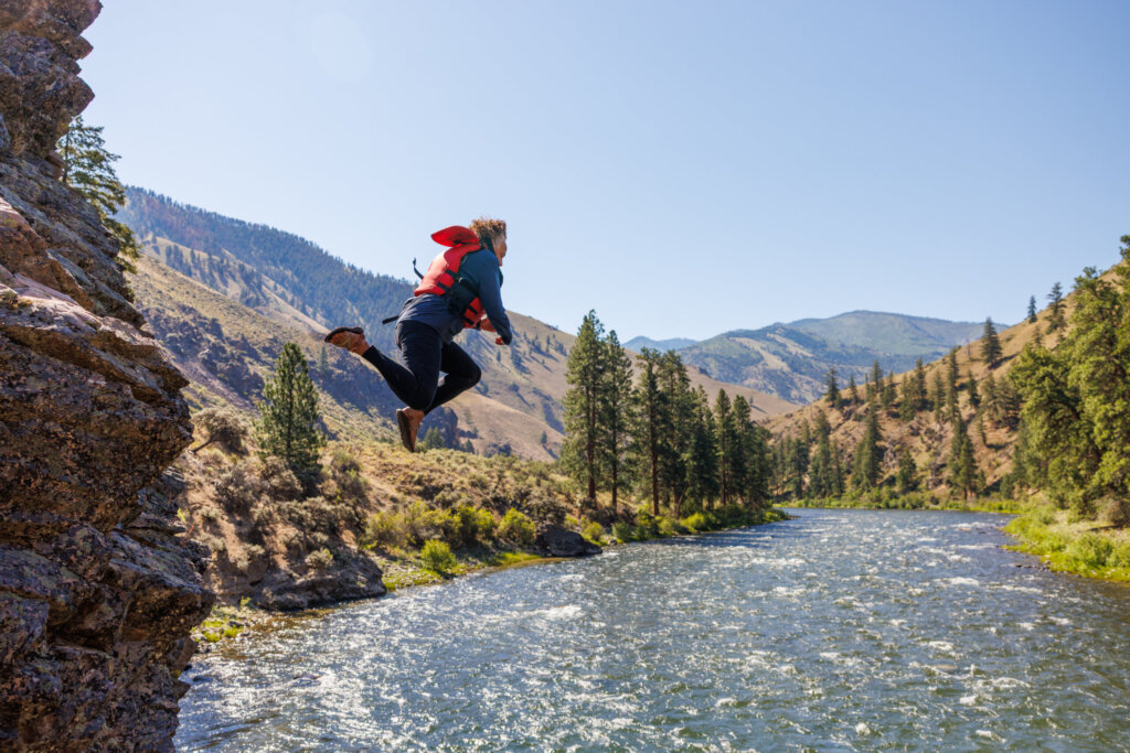 lady jumps off rock into the middle fork salmon river.