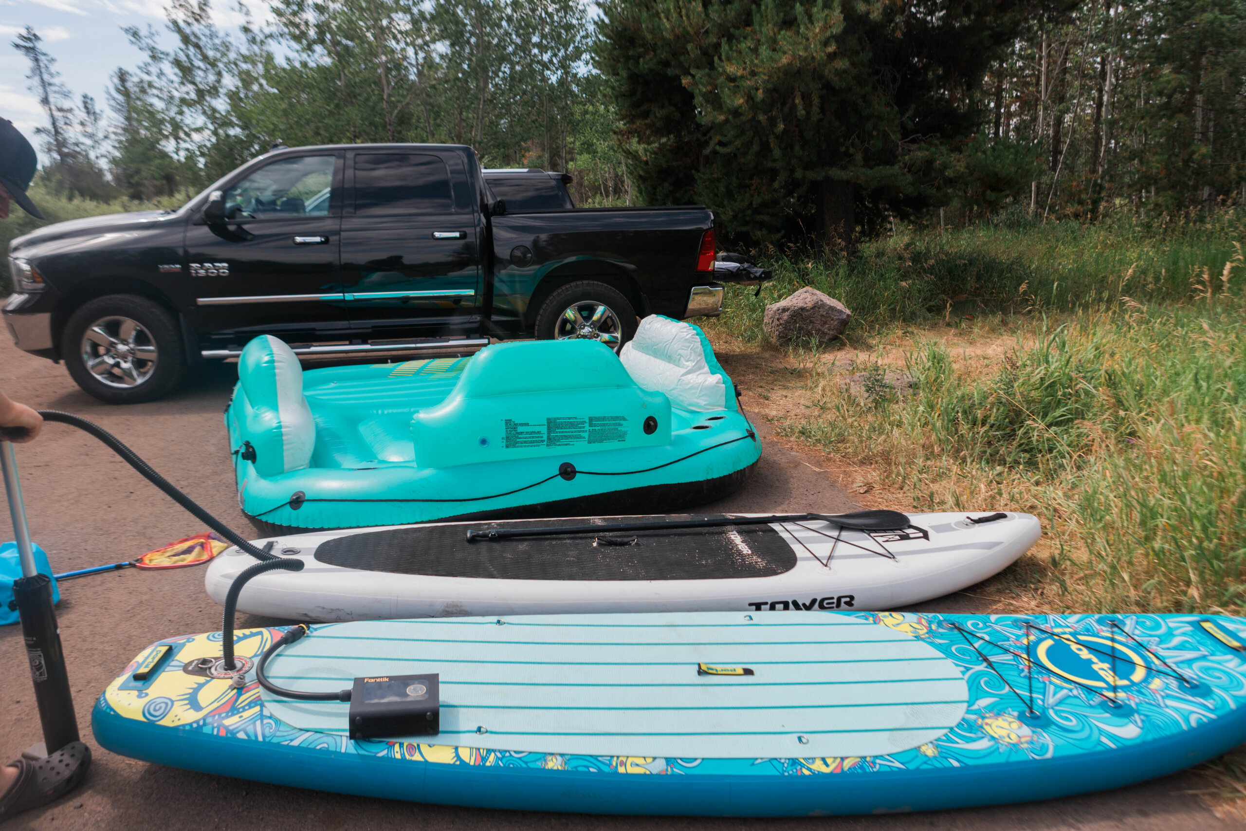 Two standup paddleboards and a large inflatable tube on the ground being inflated